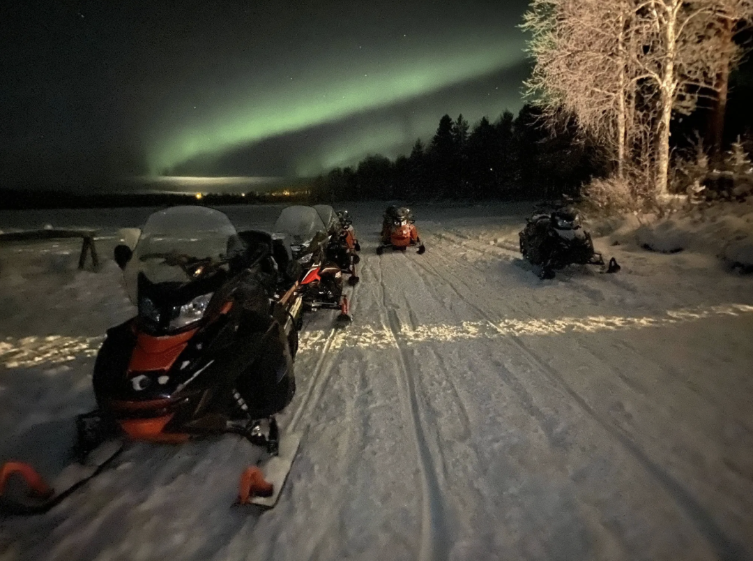 A snowmobile on a frozen lake Pyhäjärvi under the green northern lights