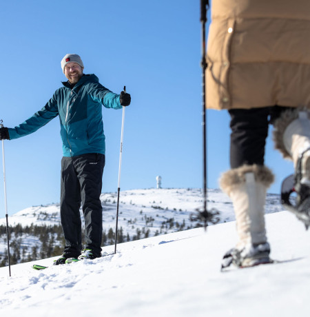 Kaksi henkilöä lumikenkäilee tunturissa