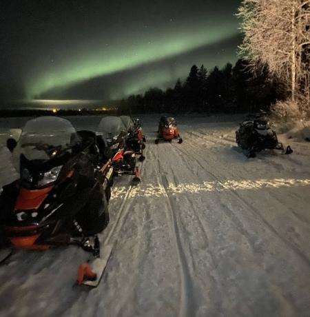 A snowmobile on a frozen lake Pyhäjärvi under the green northern lights