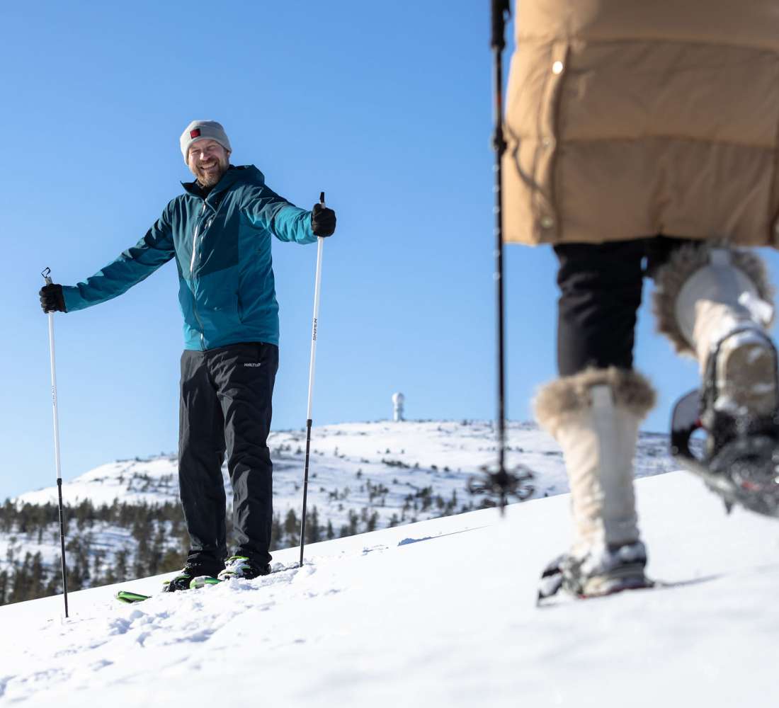 Kaksi henkilöä lumikenkäilee tunturissa