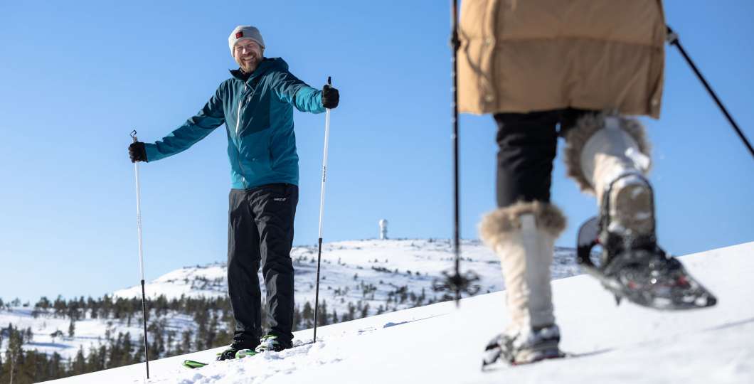 Kaksi henkilöä lumikenkäilee tunturissa